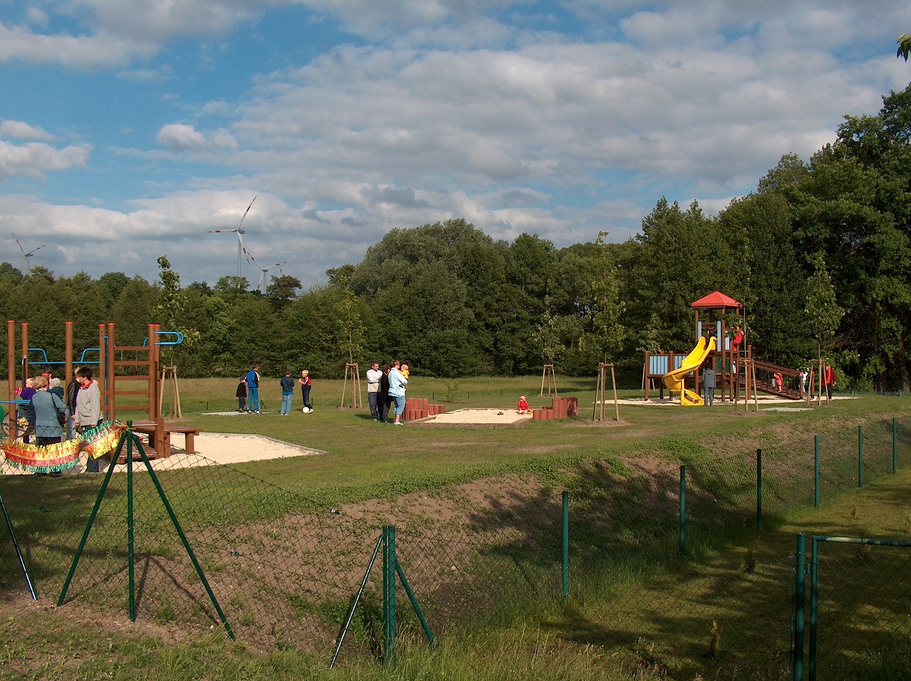 Großer Spielplatz mit modernen Geräten und Windrädern im Hintergrund, gebaut von Berthold - Bau Lauta.