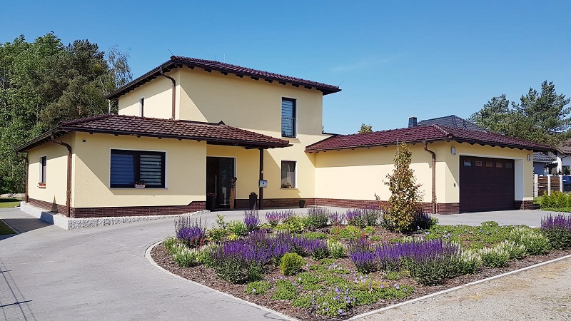 Neubau eines Einfamilienhauses mit Garage von Berthold - Bau aus Lauta, modernes Design mit Ziegeln und Zaun.