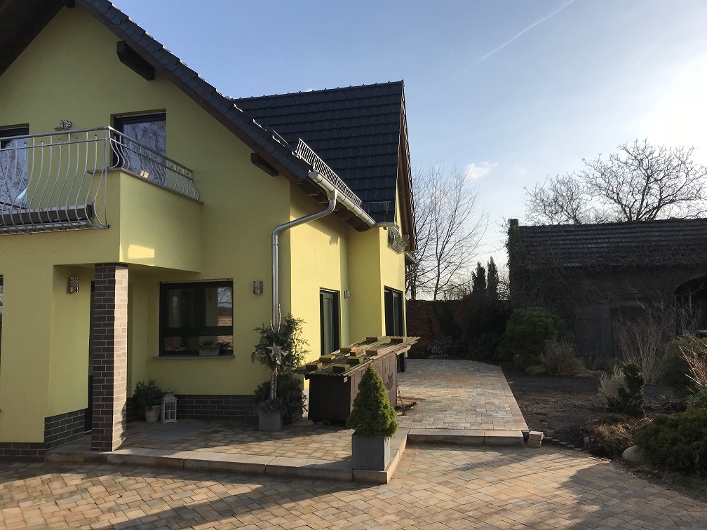 Gelbes Einfamilienhaus mit Balkon und gepflasterter Terrasse, ein Bauprojekt von Berthold - Bau aus Lauta.