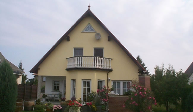 Gelbes Einfamilienhaus mit Balkon und Giebelfenster, ein Beispielbau von Berthold - Bau aus Lauta.