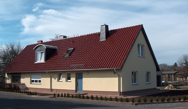 Neu gebautes Einfamilienhaus mit rotem Ziegeldach und Gauben, realisiert von Berthold - Bau aus Lauta.