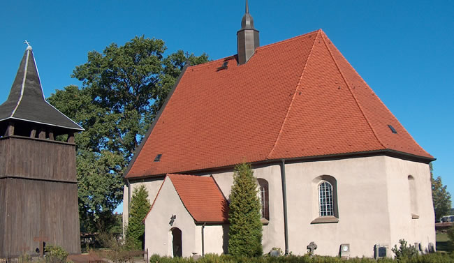 Historische Kirche mit rotem Dach und separatem Glockenturm, ein Sanierungsprojekt von Berthold - Bau aus Lauta.