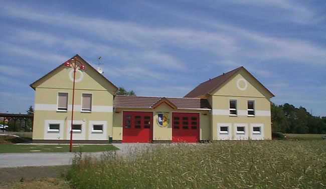Modernisiertes Feuerwehrhaus mit zwei roten Garagentoren, ein Projekt von Berthold - Bau aus Lauta.