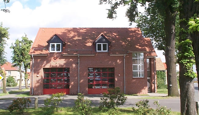 Backstein-Feuerwehrhaus mit zwei roten Toren und Gauben, ein Bauprojekt von Berthold - Bau aus Lauta.