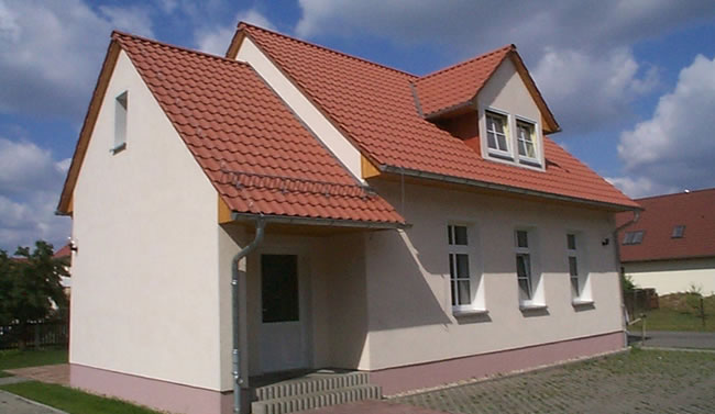 Berthold-Bau Einfamilienhaus in Lauta: modernes, barrierefreies Haus mit rotem Ziegeldach, heller Fassade und Zugang.